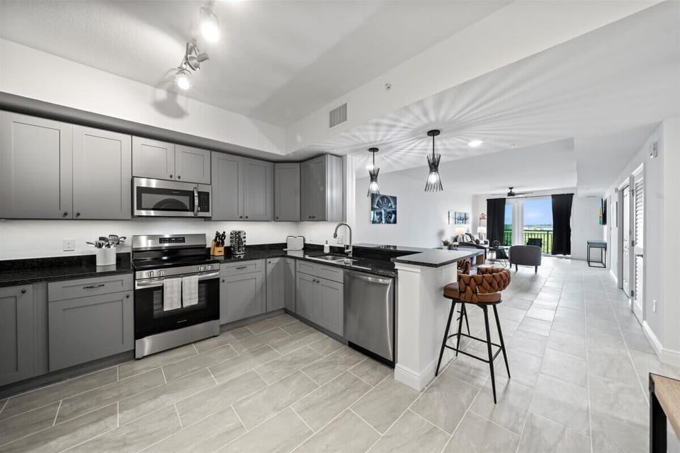 Modern kitchen with stainless steel appliances and a breakfast bar overlooking the living area.