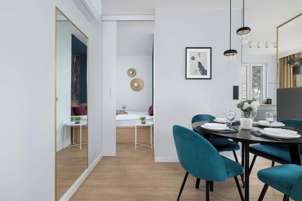 View of the living area with a round table and designer chairs. The functional layout and a large mirror visually enlarge this modern space.