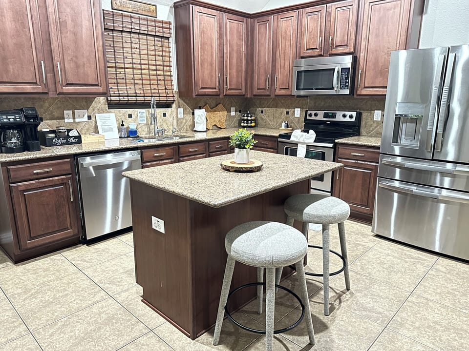 Fully stocked kitchen with island seating, stainless steel appliances, and coffe