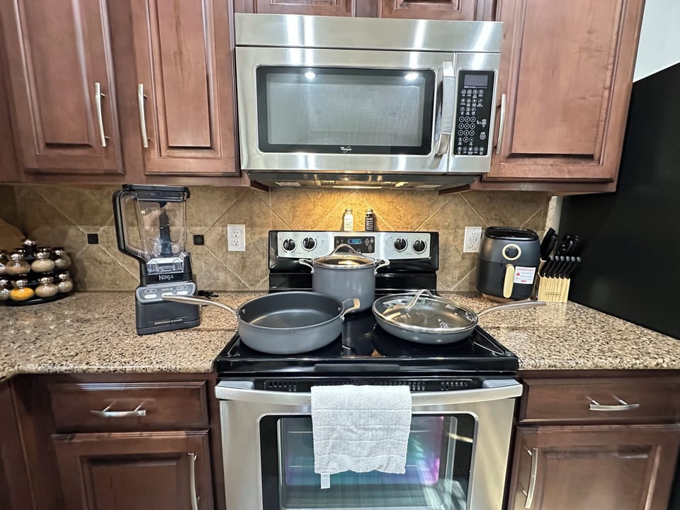 Fully equipped kitchen with cookware, air fryer, blender, and spices.