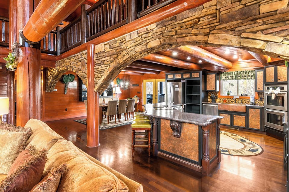 Gourmet kitchen with stone hearth, double ovens, log beams, and a huge island.