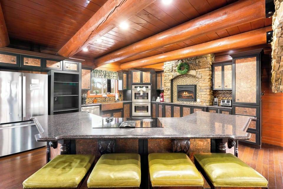 Gourmet kitchen with stone hearth, double ovens, log beams, and a huge island.