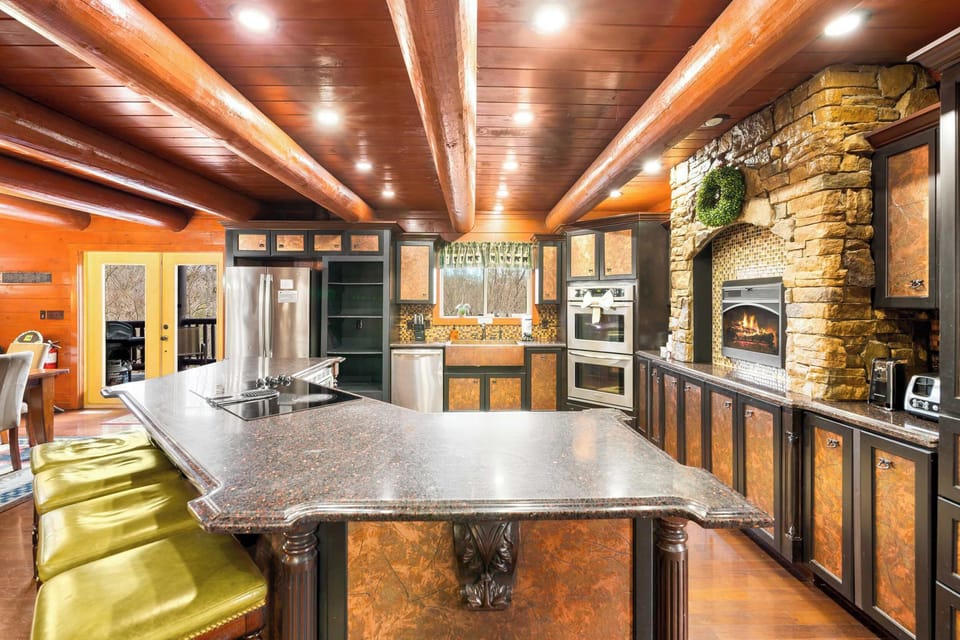 Gourmet kitchen with stone hearth, double ovens, log beams, and a huge island.
