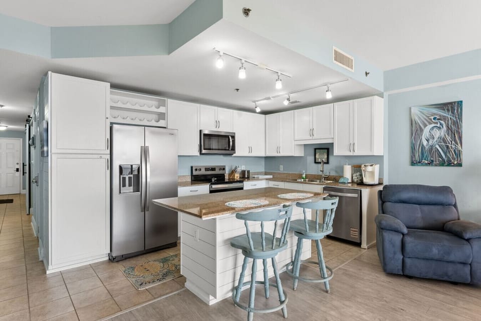 Spacious, fully equipped coastal kitchen with stainless steel appliances and a large island perfect for cooking and gathering.