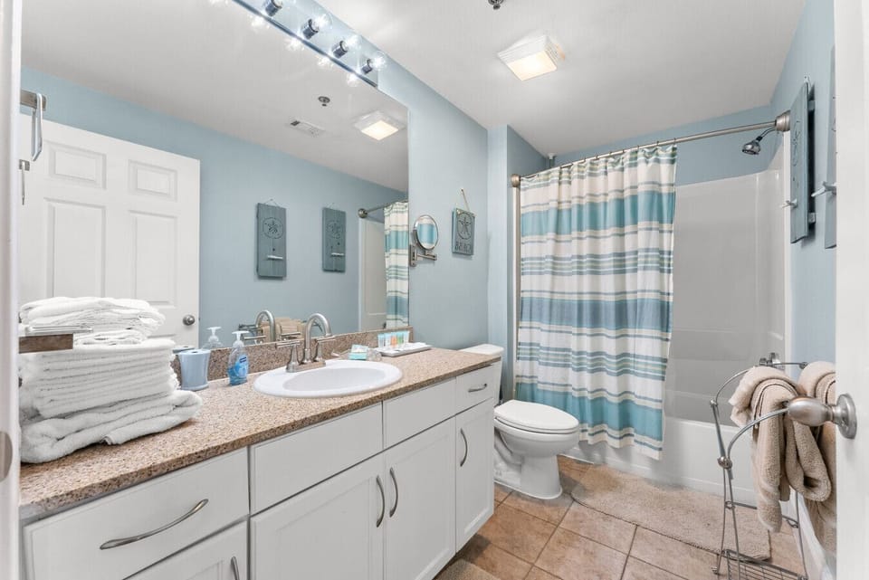Spacious coastal bathroom with a full tub/shower combo, large vanity, and plenty of fresh towels for your stay.