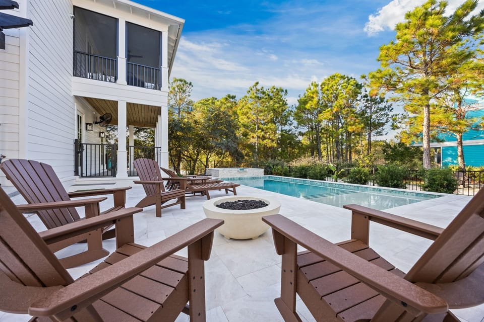 Gather the group around the fire bowl once the sun goes down — Adirondack chairs, pool glow, and pines all around you.