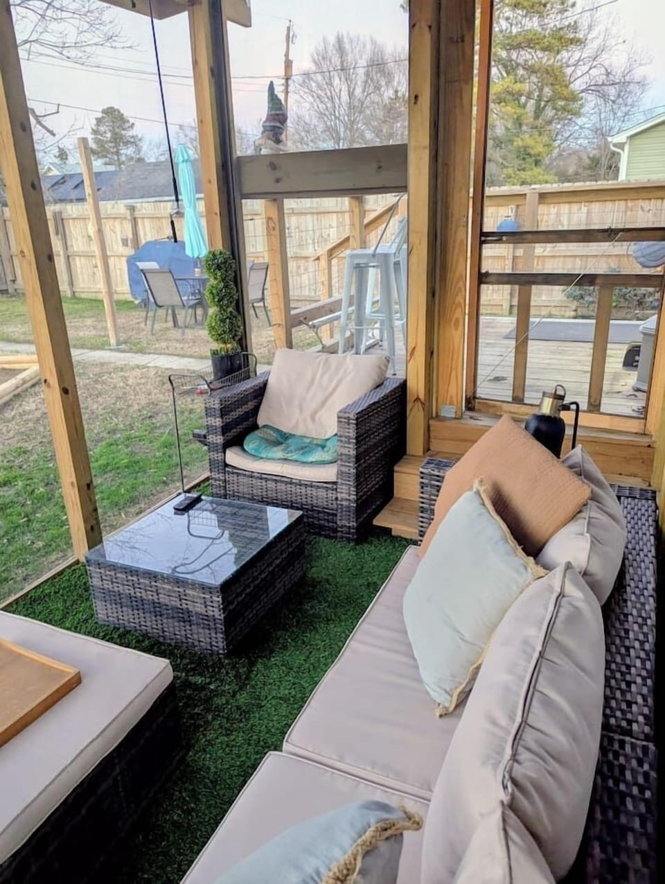 The screened‑in patio is a cozy hideaway with a mounted Roku TV, string lights, and padded wicker seating. Afternoon shade, porch blinds, and a portable fan make it the perfect spot to unwind. Gnomies, rejoice!