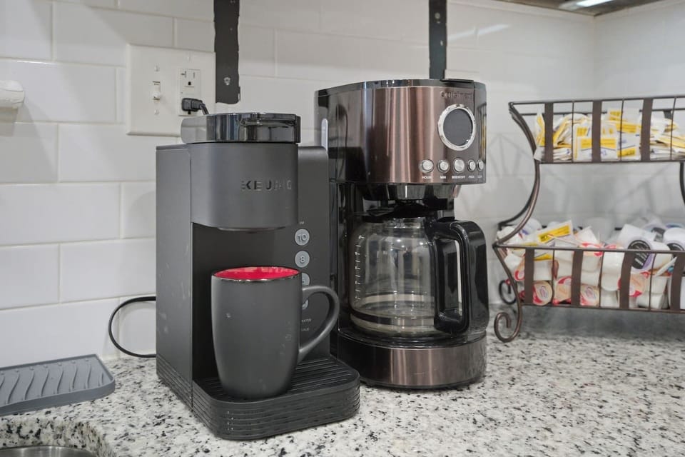 A bright, modern kitchen with granite counters, stainless appliances including a large double door fridge-freezer combo, and a fully stocked coffee bar. Laundry room and direct access to the backyard make this space flow for those on the go!