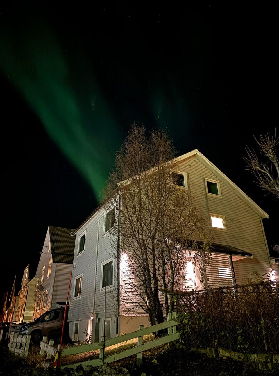 Bilde av fasaden med Nordlys over hustaket. Bilde fra oktober 2025.