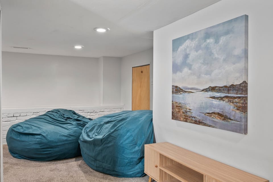 Downstairs via a twisting carpeted staircase is the Grotto.  A 6' high finished room with large bean bag chairs sofa, Smart TV and lots of room for teen or kid gatherings, gaming, games, sleepovers, etc.