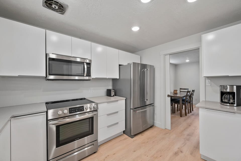 A large kitchen with lots of counter top space, modern stainless steel appliances and fully stocked with many modern conveniences