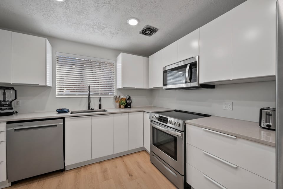 A large kitchen with lots of counter top space, modern stainless steel appliances and fully stocked with many modern conveniences