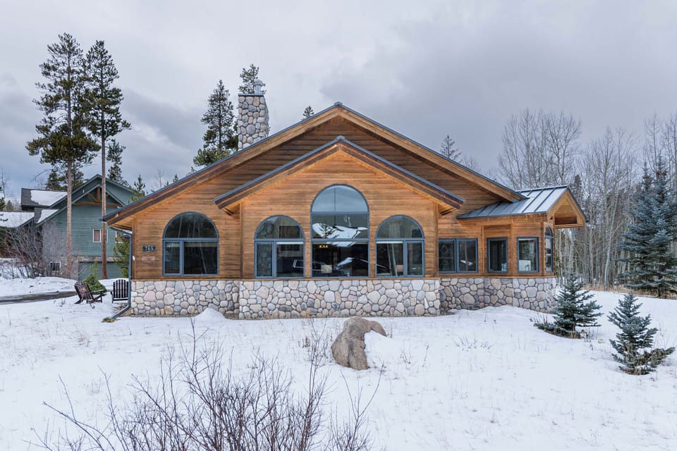Mountain retreat featuring rustic wood and stone architecture nestled among snow-covered evergreens.
