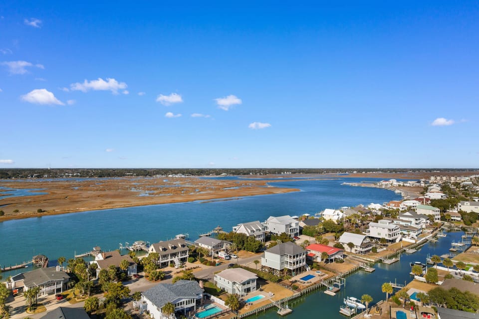 Stunning aerial view of the waterfront community featuring charming coastal homes, private docks, and pristine blue waters stretching to the horizon.