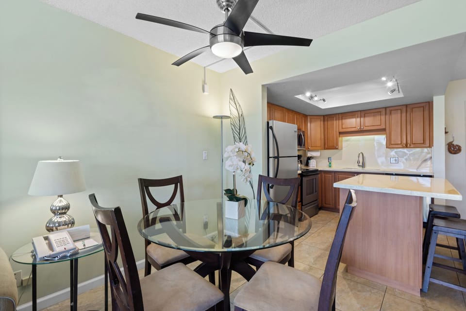 Enjoy meals in your elegant dining space featuring a glass table, modern ceiling fan, and fully equipped kitchen with granite counters.