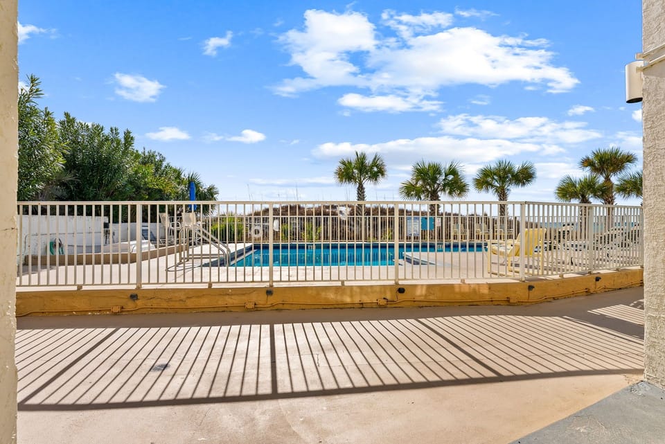 Your private deck overlooks the sparkling pool area, where tropical palms frame azure waters under endless Carolina skies.