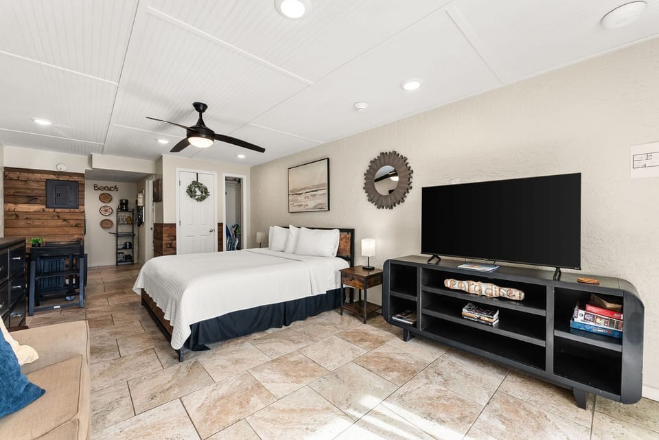 Relax in your spacious bedroom featuring a cozy king bed, large TV, and rustic coastal decor that makes you feel right at home.