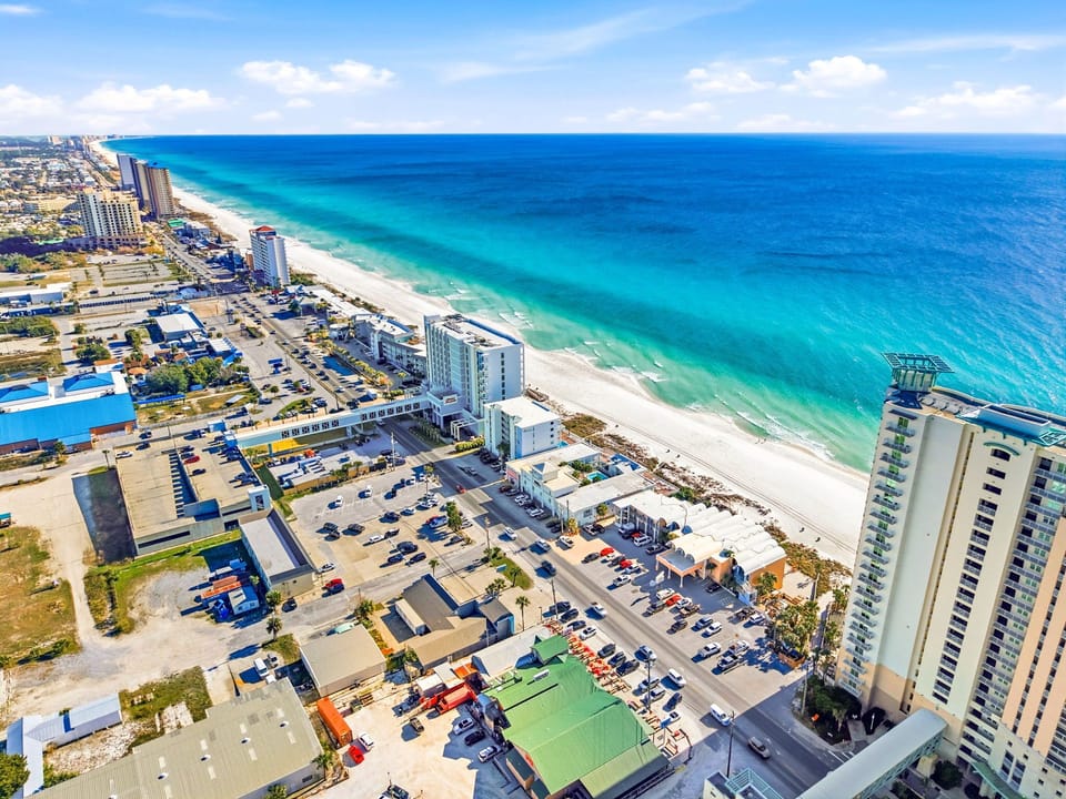 Aerial view of pristine white sand beach with turquoise waters and nearby beachfront hotels and restaurants.