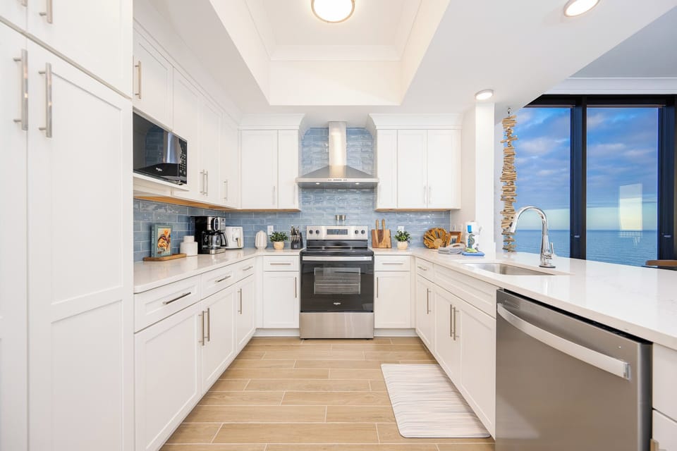 Prepare meals in this stylish kitchen featuring stainless appliances and a stunning beach view