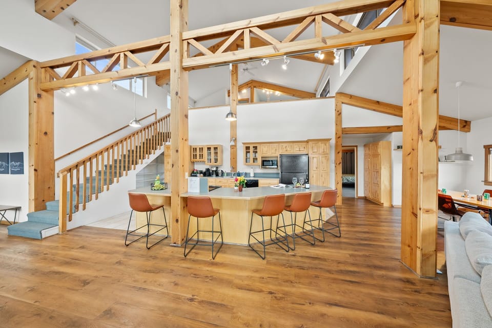 Open dining area with bar seating, wood beams, and kitchen access
