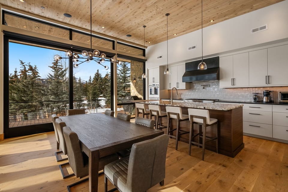 Your gourmet kitchen flows seamlessly into dining space, where morning coffee tastes better with mountain views through floor-to-ceiling windows.