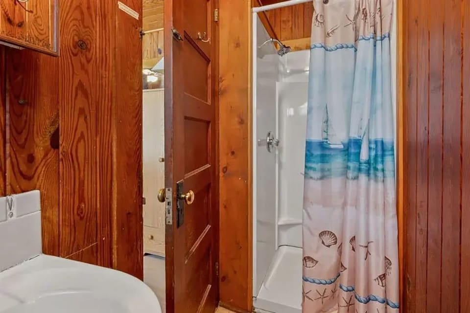 A wood-paneled bathroom with a stand-up shower and a white toilet.