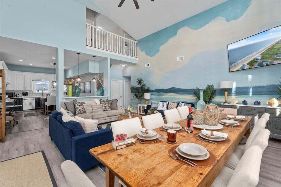 Living and dining area with open layout, large table, and ocean mural wall – perfect for entertaining.