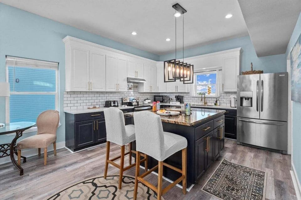 Spacious kitchen with granite countertops, two door refrigerator, bar stools, and open dining connection – family-friendly layout.