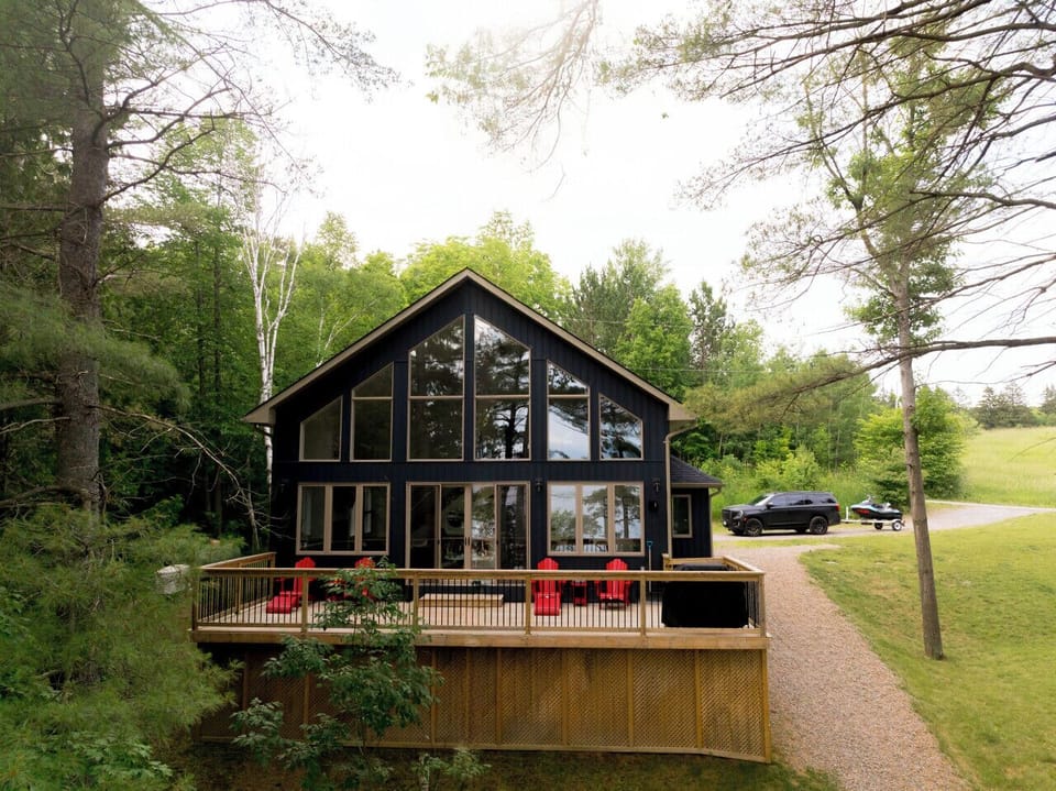 Large outdoor deck featuring a BBQ and Adirondack chairs, overlooking the lake with beautiful waterfront views.