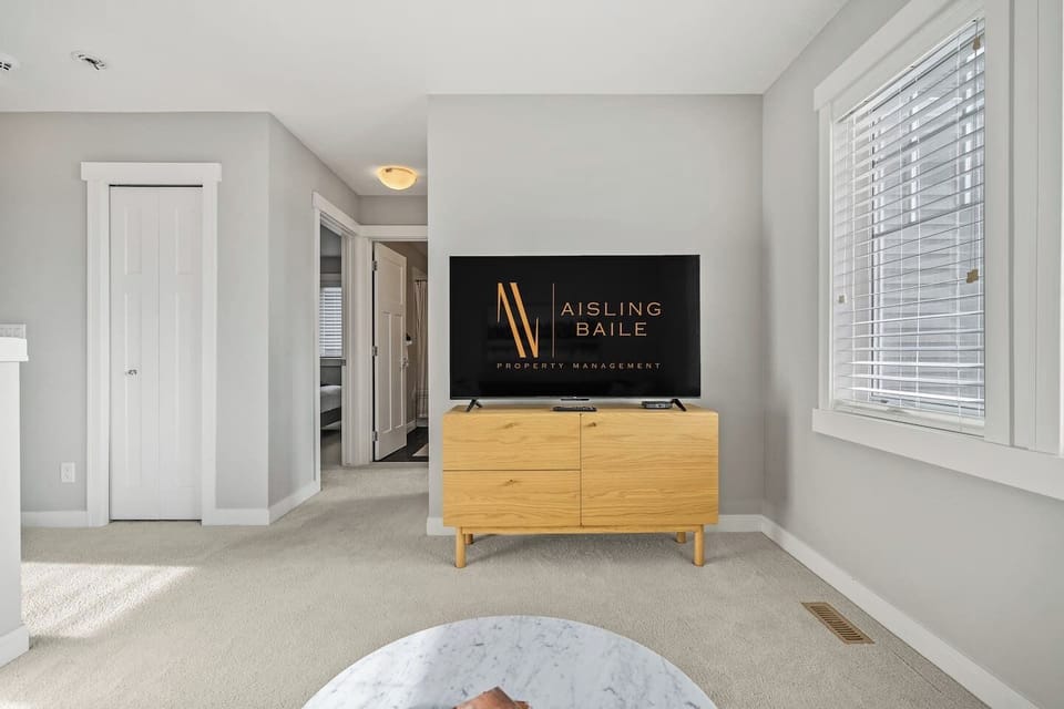 Upper-level living room/den area with a cozy couch and Smart TV.