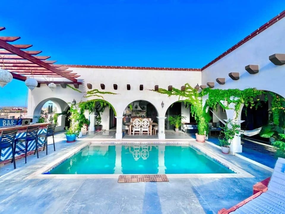 Expansive ocean-view patio featuring a heated pool, outdoor kitchen/BBQ, dining area for 6, bathroom with open-air shower, loungers, hammocks, and quiet corners ideal for reading, relaxing, or whale-watching.