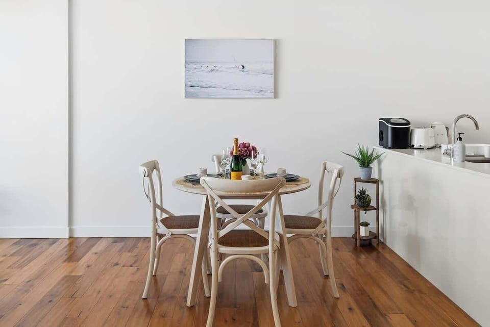 Dining area with round wooden table set for four, floral centerpiece and minimalist design creating a bright and welcoming space.