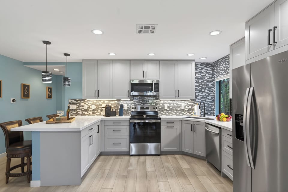 Kitchen features modern appliances and barstool seating.