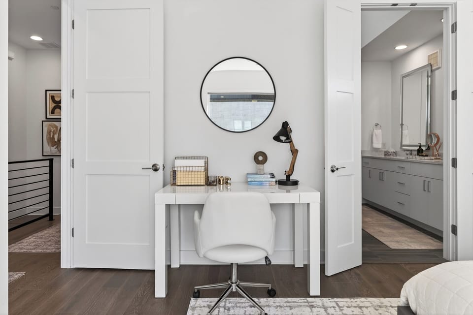Clean and modern home office nook with a white table and round mirror.