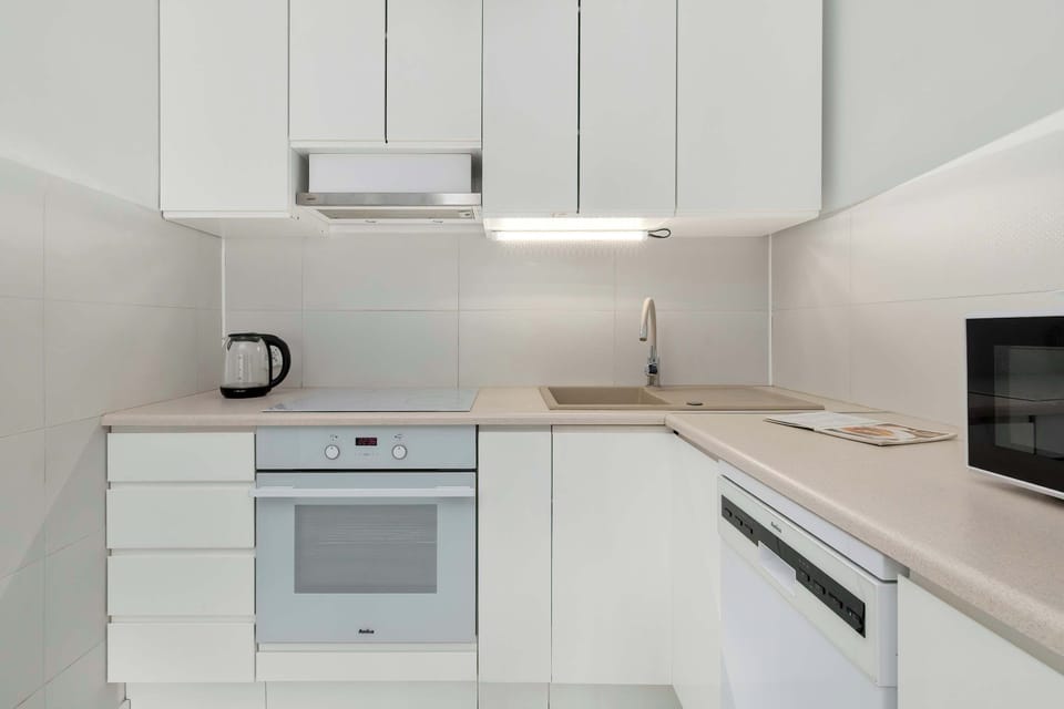 Minimalist white kitchen with sleek cabinets and built-in appliances.