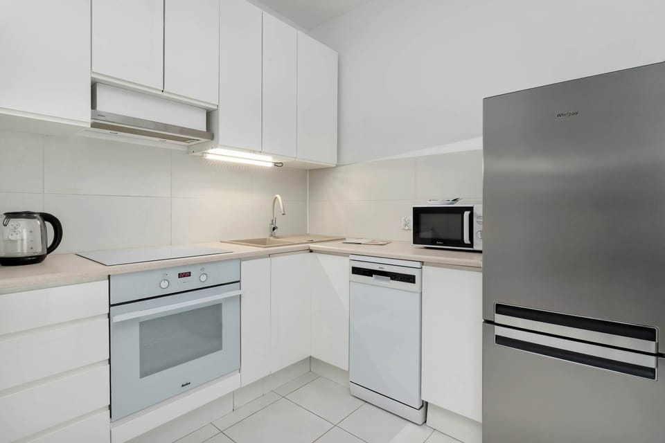 Minimalist white kitchen with sleek cabinets and built-in appliances.