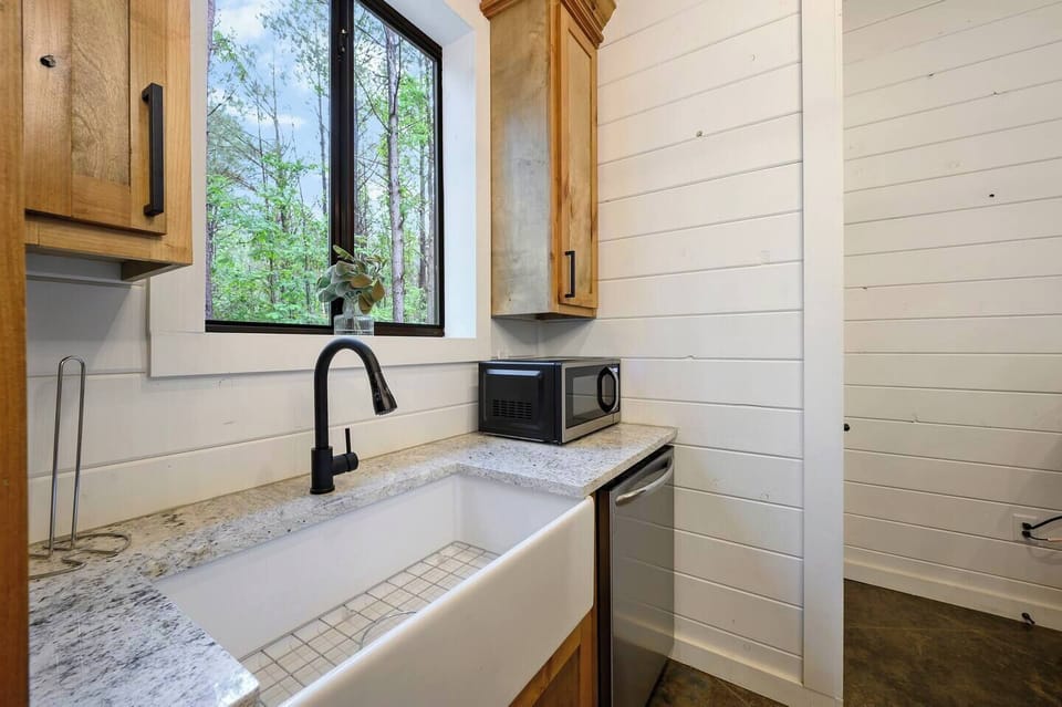 A modern farmhouse kitchen featuring a deep apron sink, sleek finishes, and a window that brings the outdoors inside.