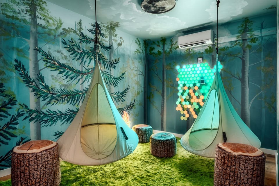 Glow-in-the-dark forest hideout where kids claim hanging pod “nests,” sprawl on the soft grass floor, and fall asleep under a moonlit sky and color-changing lights that feel straight out of a storybook.