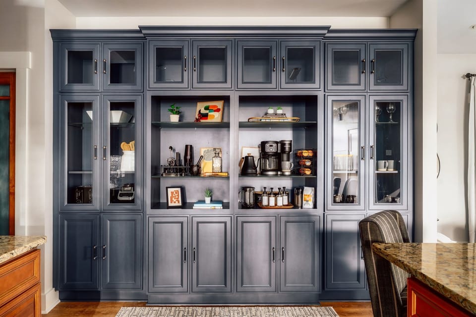 Floor-to-ceiling coffee and cocktail wall stocked with syrups, mugs, glassware, and bar tools—wake up to your perfect latte and wind down with a crafted nightcap without ever leaving the house.