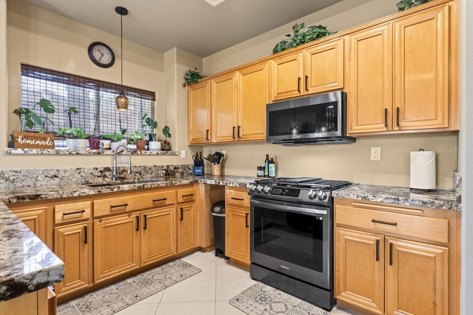 Chef-style kitchen w/ wood cabinetry, granite counters & stainless appliances for easy meal prep