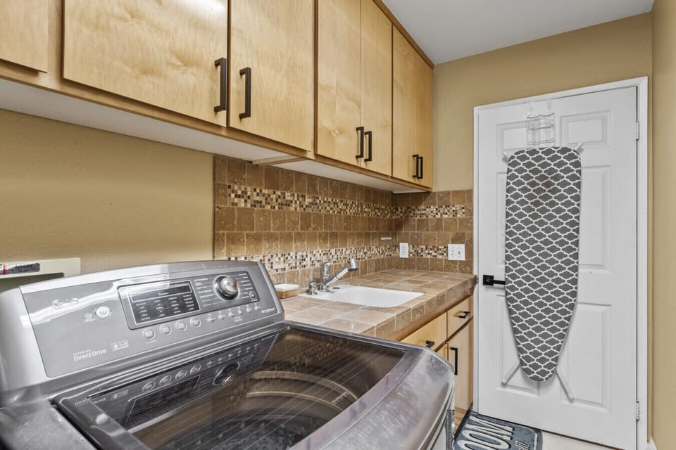 Laundry area w/ washer, dryer & overhead cabinets for convenient mid-stay refresh