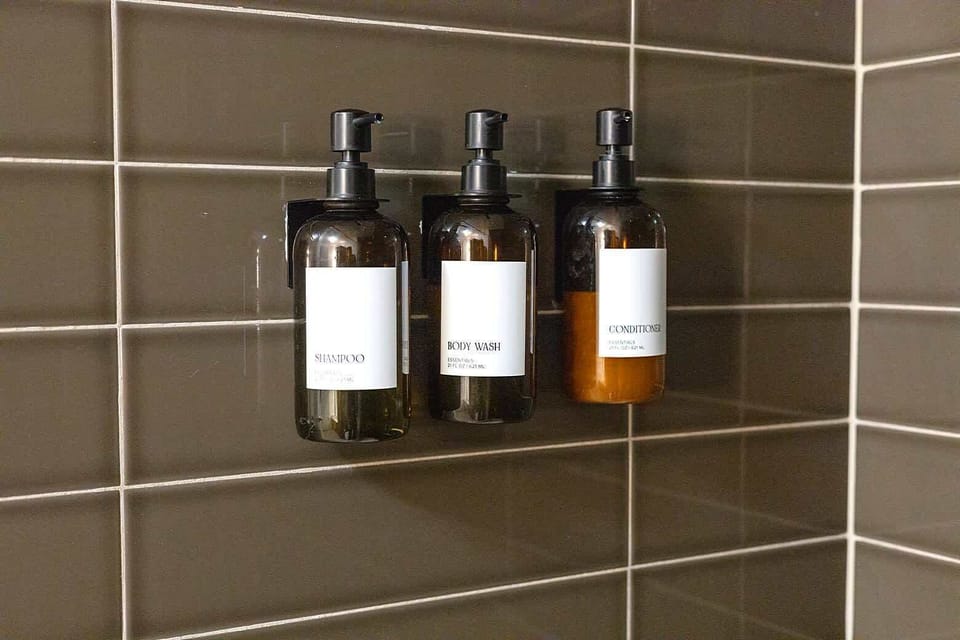 Clean and modern bathroom with tiled shower walls and mounted toiletries for guest convenience. Designed with a sleek look and practical layout to ensure a refreshing and comfortable daily routine.