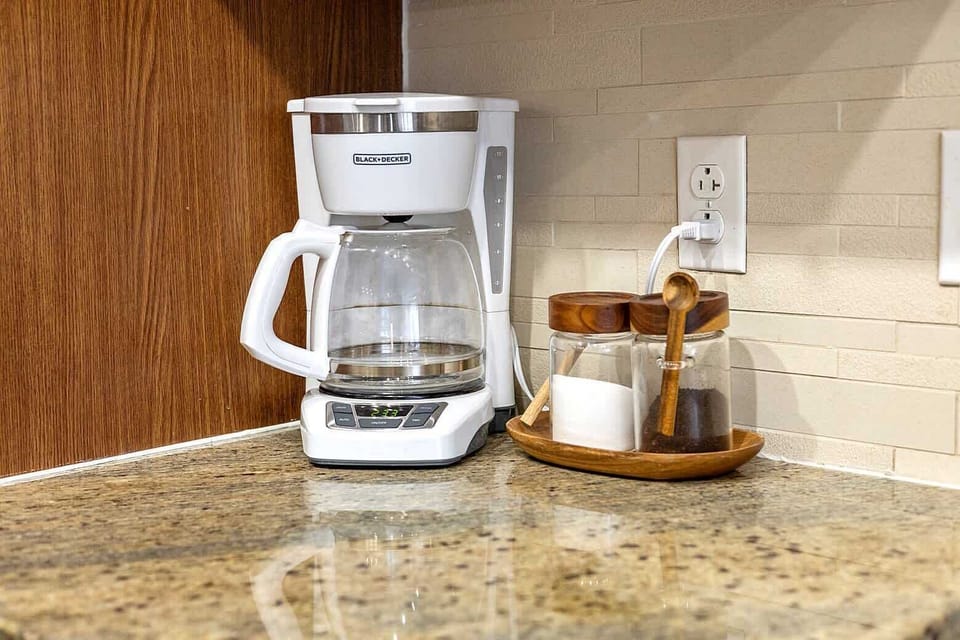 Well equipped kitchen counter featuring a coffee maker and starter essentials. Perfect for morning routines or quick refreshment breaks, offering a functional and tidy space to begin your day.