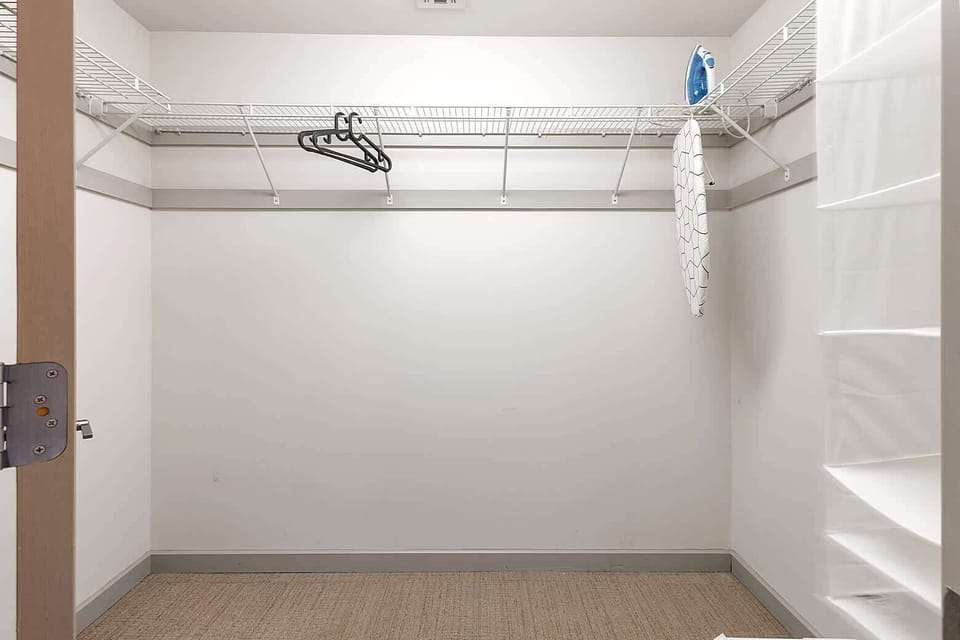 Generous walk in laundry and storage room with shelving and hanging racks. Ideal for organizing luggage, storing clothes, or handling laundry with ease during extended visits.