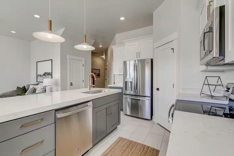 Fully stocked kitchen with upgraded appliances and thick solid-surface countertops opening to the living room
