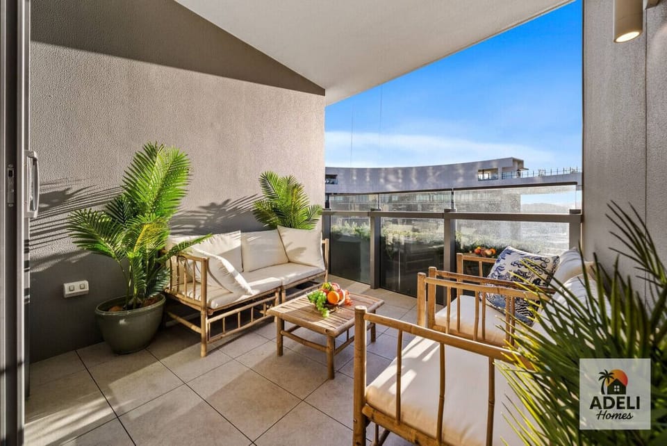Sunny balcony with cozy seating, lush plants, and skyline views — a perfect spot to unwind with morning coffee or evening wine.