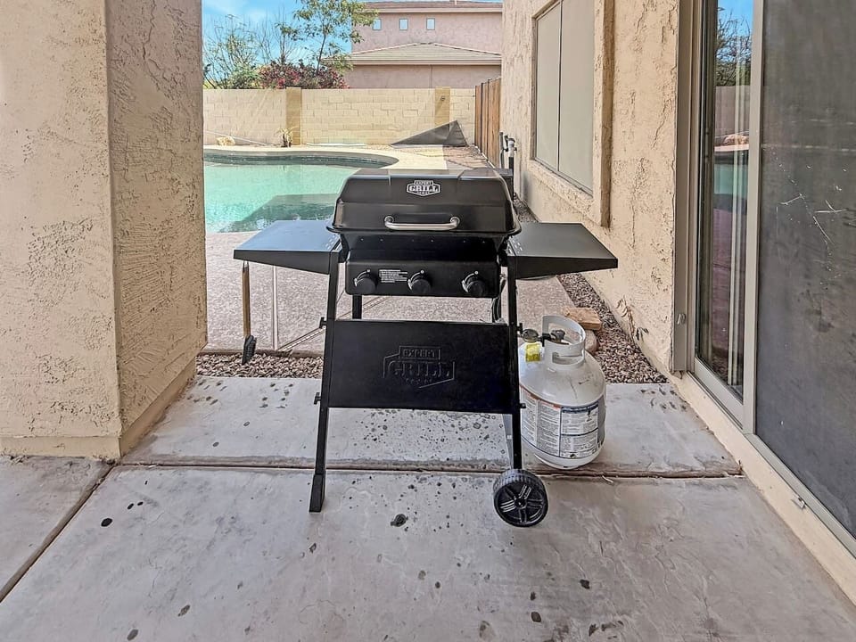 Covered patio with grill beside sliding door and pool view