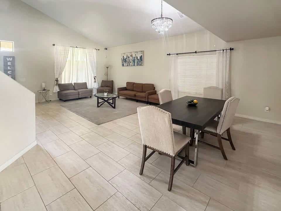 Open dining and living area with sofa, table, and chandelier