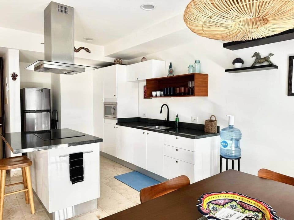 Enjoy a fully equipped kitchen with modern cabinetry and a kitchen island with stools, offering everything you need to prepare meals. Includes a stove, refrigerator, microwave, coffee machine, toaster, blender, and drinking water.