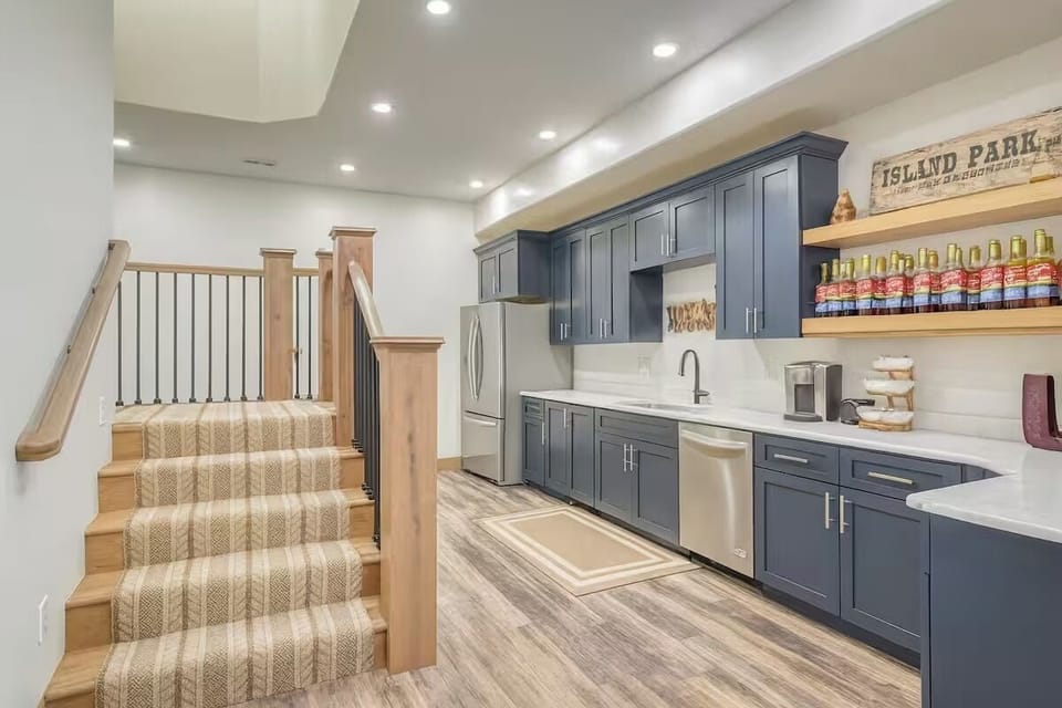 Convenient kitchenette with modern cabinetry, full-size appliances, near stairs.
